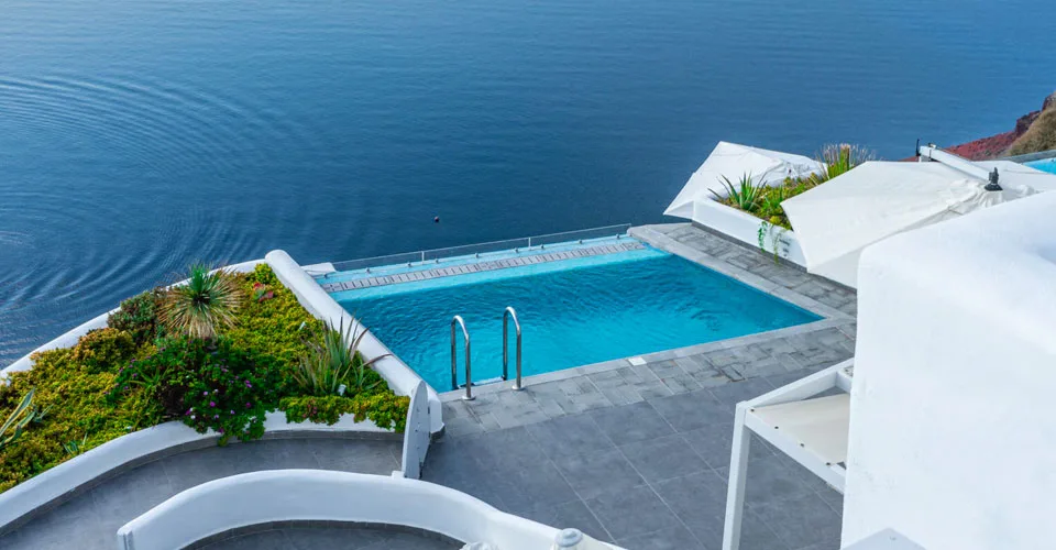 Urlaub Griechenland. Terrasse mit weißen Mauern und Blick aufs Meer – mediterrane Architektur in Griechenland