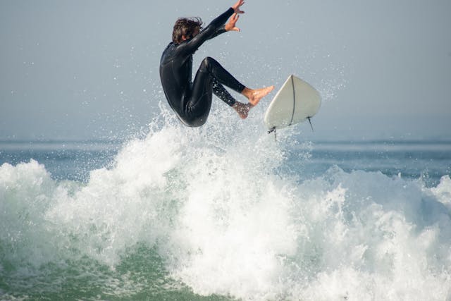 Portugal Urlaub am Meer. Surfer auf einer Welle vor der portugiesischen Küste – Sinnbild für einen spontanen Last-Minute-Urlaub am Meer