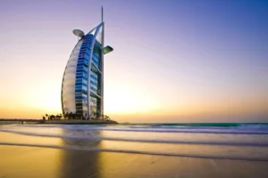 Hotel buchen. Burj Al Arab bei Sonnenuntergang mit Blick auf Strand und Wasser – Symbol für Luxus und kulinarische Erlebnisse in Dubai.