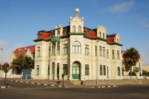 Kolonialgebäude mit rotem Dach und Palmen in Swakopmund – Küstenstadt in Namibia mit Strand und Wüstenflair