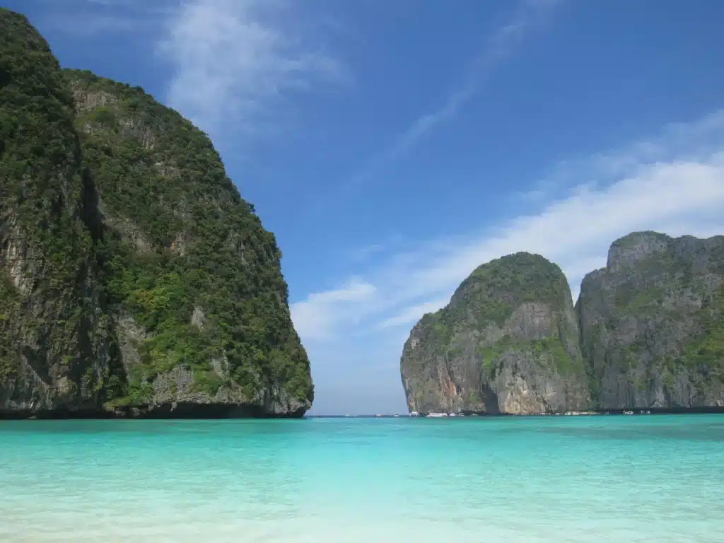 Thailand Urlaub. Tropischer Strand mit weißem Sand, türkisfarbenem Wasser und grünen Kalksteinfelsen – typische Inselkulisse in Thailand.