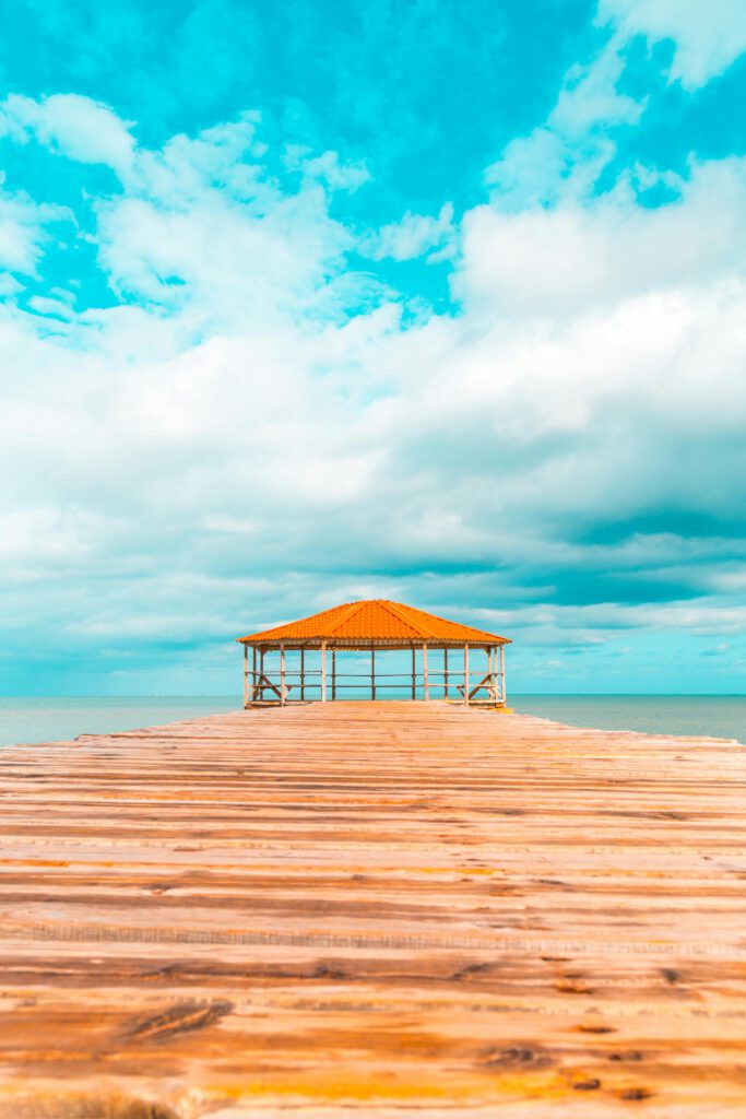 Holzpavillon über türkisblauem Meer unter karibischem Himmel – Sinnbild für entspannte All-Inclusive-Auszeit in der Karibik.