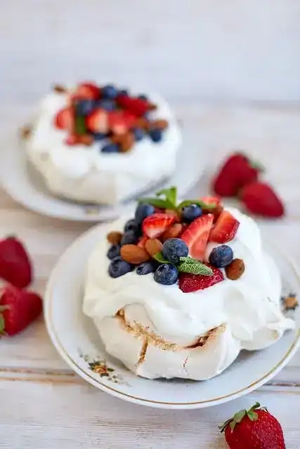 Pavlova Dessert mit Sahne, Erdbeeren, Blaubeeren und Minze – australische Spezialität