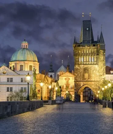 Karlsbrücke in Prag bei Abendstimmung mit beleuchteten Statuen und Altstadt
