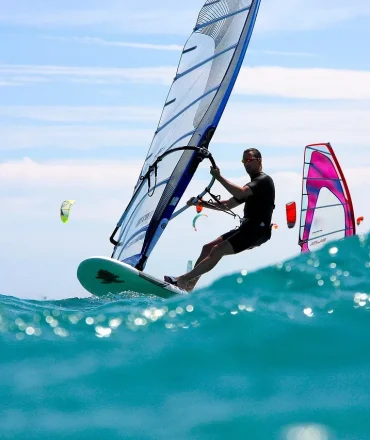 Fuerteventura Urlaub. Windsurfer auf türkisblauem Meer vor Fuerteventura bei sonnigem Wetter – Aktivurlaub auf den Kanaren