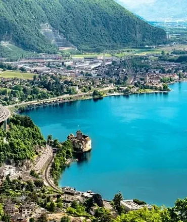 Genfersee mit Alpenkulisse und Uferstadt bei Sonnenschein
