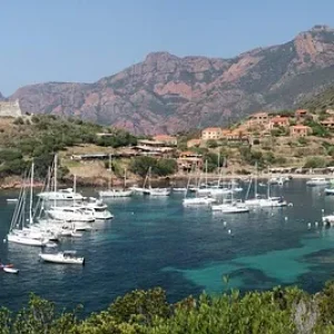Korsika Rundreise. Küste von Korsika mit Segelbooten vor grünen Bergen – Bootstour nach Girolata und ins Scandola-Reservat