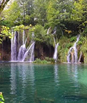 Kaskadierende Wasserfälle im Plitvice Nationalpark, umgeben von türkisblauen Seen und dichter Vegetation
