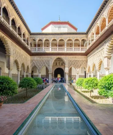 Innenhof des Real Alcázar in Sevilla mit maurischen Bögen, Spiegelbecken und kunstvoller Fassadengestaltung