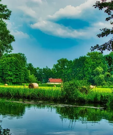Urlaub Ostdeutschland. Spreewald-Fließ mit grüner Ufervegetation und Spiegelung im Wasser