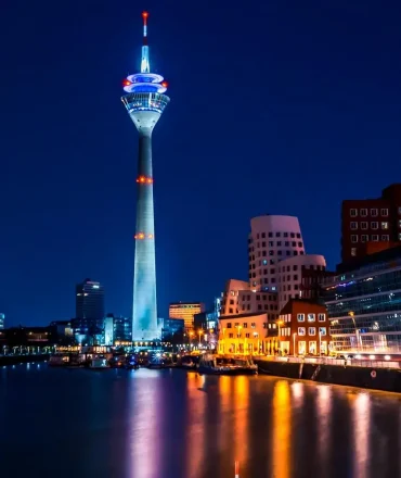 Städtereise Düsseldorf. Düsseldorfer Skyline mit beleuchtetem Rheinturm und Rhein bei Nacht
