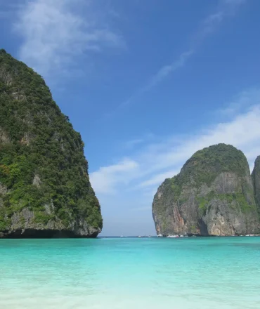 Thailand Urlaub. Tropischer Strand mit weißem Sand, türkisfarbenem Wasser und grünen Kalksteinfelsen – typische Inselkulisse in Thailand.