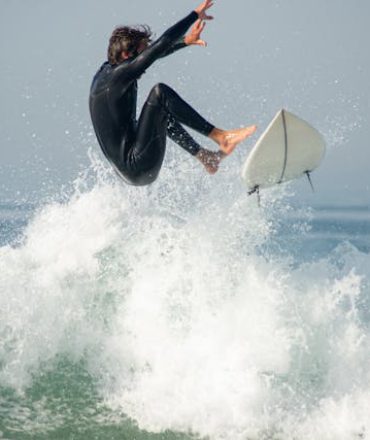 Portugal Urlaub am Meer. Surfer auf einer Welle vor der portugiesischen Küste – Sinnbild für einen spontanen Last-Minute-Urlaub am Meer