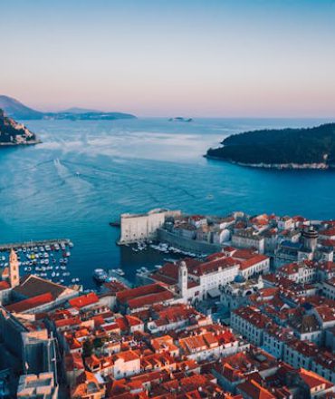 Kroatien Urlaub. Luftaufnahme einer kroatischen Küstenstadt mit roten Dächern, Hafen und Inseln im Sonnenlicht