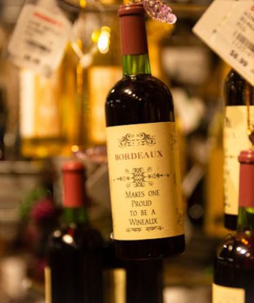 Weinreise durch Frankreich mit Fokus auf Bordeaux, Burgund und Champagne – Weinflasche und Glas im Vordergrund