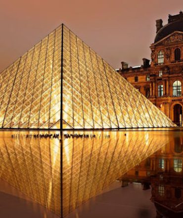 Louvre Pyramide in Paris bei Nacht, beleuchtet vor dem historischen Museum