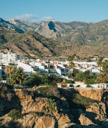 Küstenstadt in Spanien mit weißen Häusern und Bergkulisse unter blauem Himmel