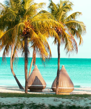 Urlaub Kuba. Weiße Sandstrände mit Palmen und Lounge-Cabanas vor türkisblauem Meer – tropisches Strandparadies in Varadero, Kuba.